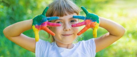 girl with colored finger paint on her hands