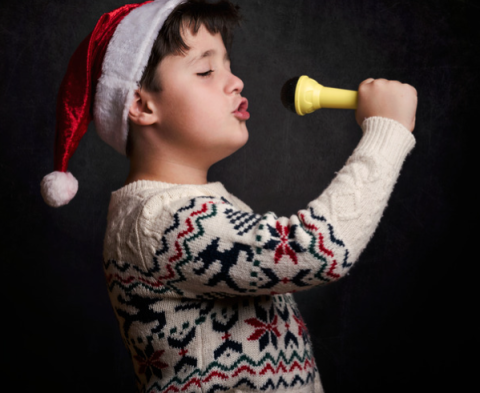 child in a santa hat singing into a microphone