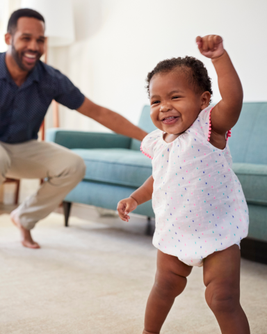 baby dancing with father in background