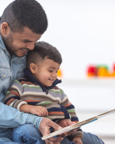 Father holding son in lap and reading a picture book