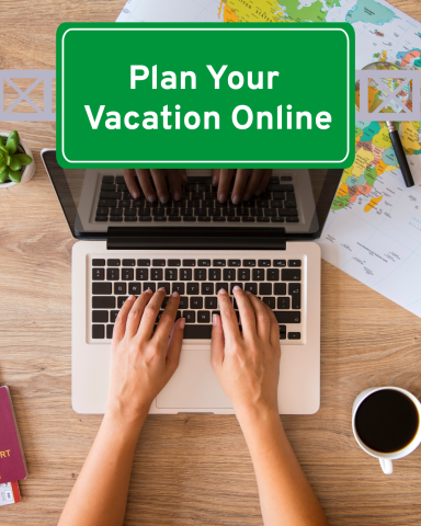 Person on laptop surrounded by map, passport and travel accessories