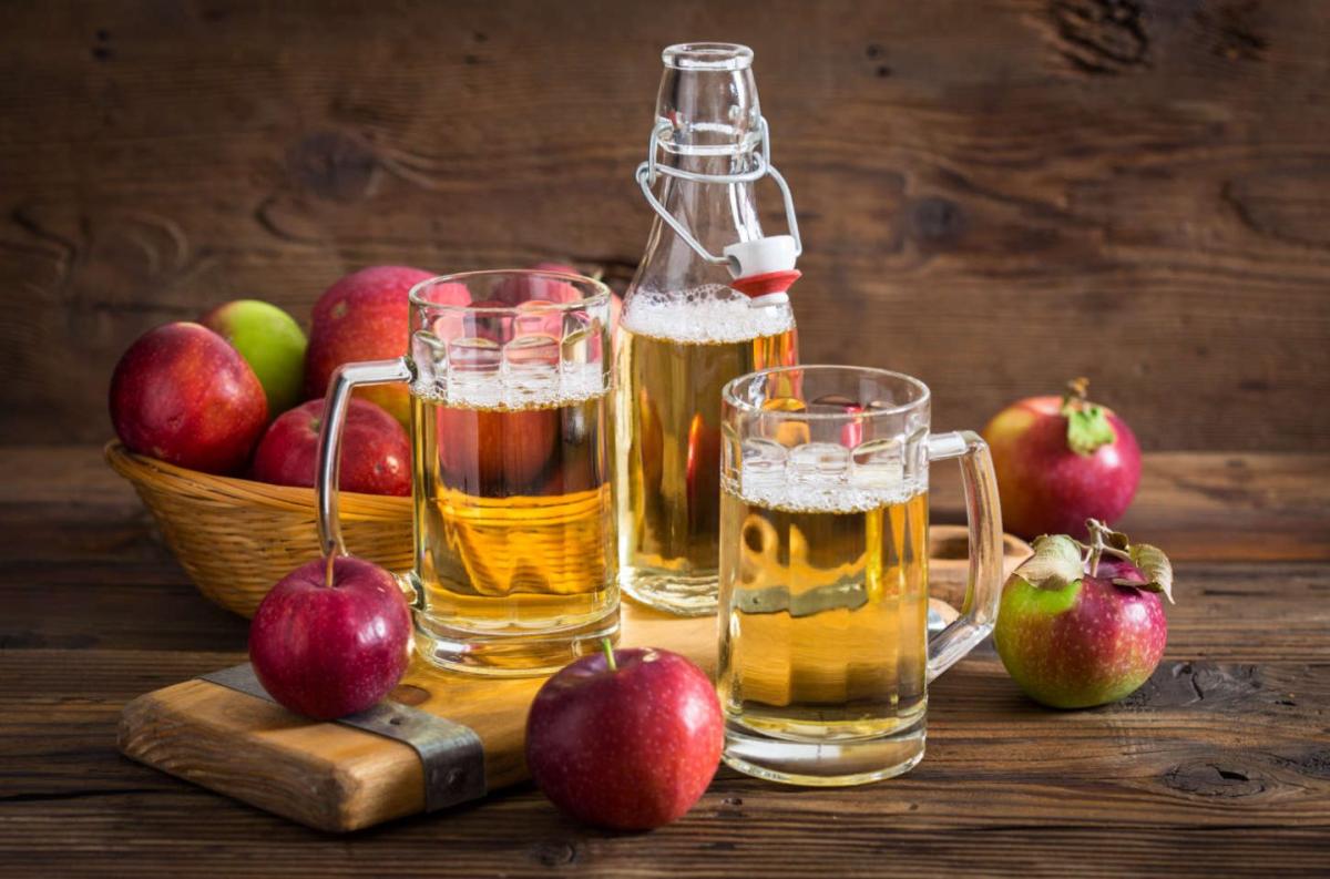 Picture of hard cider in bottles and a basket of red apples