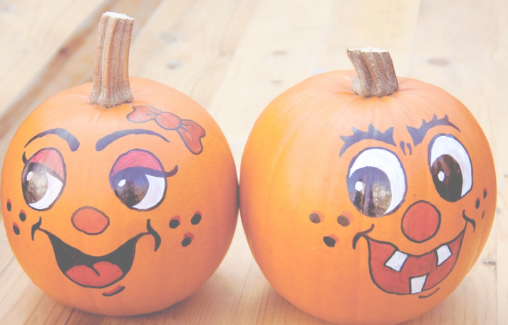 Two mini pumpkins with painted on goofy faces